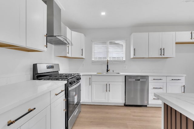 424 W Menlo Ave, Clovis, CA 93612 - kitchen with stainless steel appliances, a sink, wall chimney range hood, white cabinets, and light wood-style floors