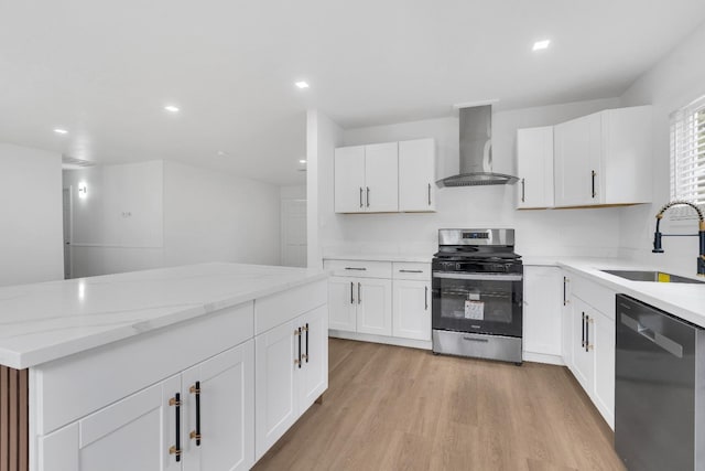 424 W Menlo Ave, Clovis, CA 93612 - kitchen featuring wall chimney exhaust hood, appliances with stainless steel finishes, a sink, light wood-style flooring, and white cabinetry