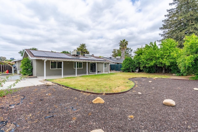 424 W Menlo Ave, Clovis, CA 93612 - rear view of property featuring stucco siding, a patio, solar panels, a lawn, and central AC