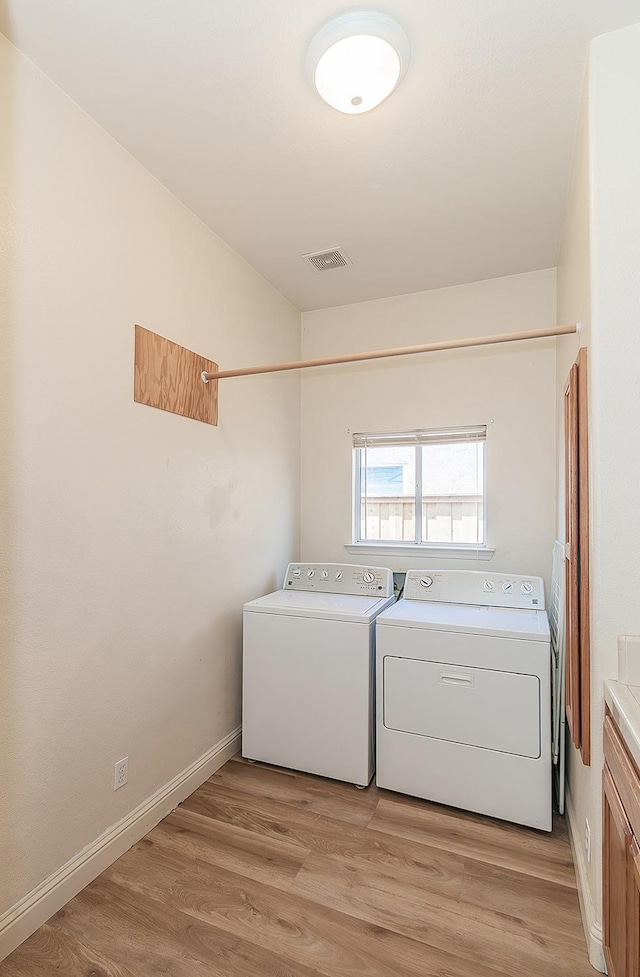 laundry area with separate washer and dryer, cabinet space, and light wood-style flooring
