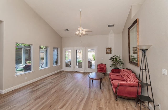 living room featuring light wood finished floors, baseboards, ceiling fan, and high vaulted ceiling