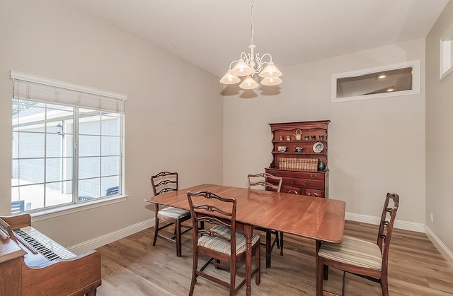 dining area featuring a chandelier, baseboards, and light wood finished floors