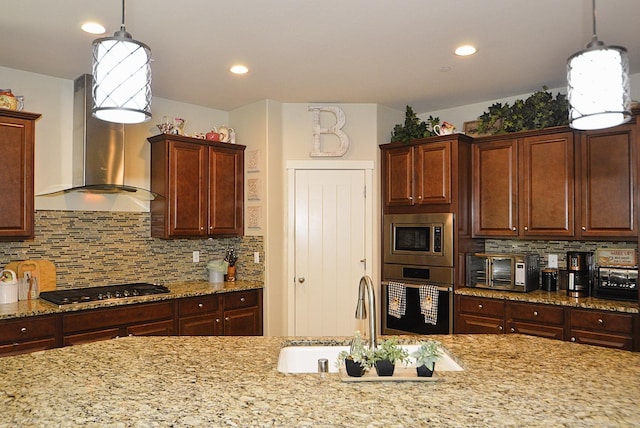 kitchen with stainless steel appliances, wall chimney range hood, a sink, decorative backsplash, and recessed lighting