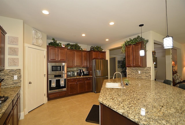 kitchen with appliances with stainless steel finishes, a sink, tasteful backsplash, a peninsula, and light stone counters