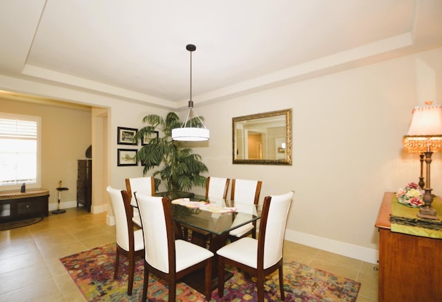 dining space featuring a tray ceiling and light tile patterned floors
