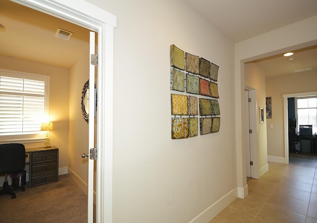 hall with baseboards, an office area, and light tile patterned floors