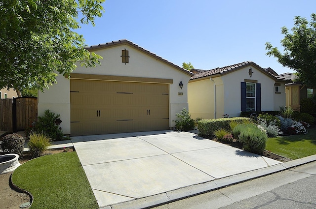 view of front of property featuring stucco siding, driveway, a garage, a tiled roof, and fence