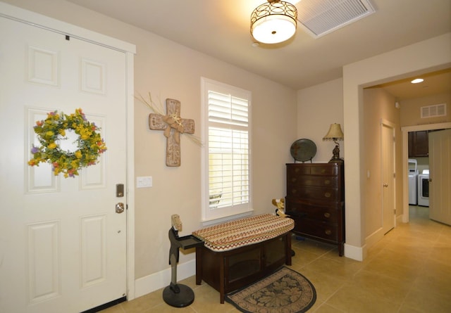 foyer featuring light tile patterned floors, washer / dryer, and baseboards