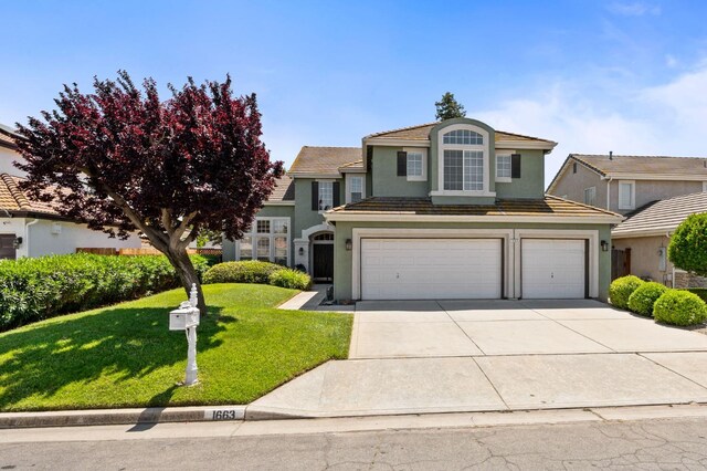 traditional-style home with a garage, driveway, stucco siding, a front yard, and a tiled roof