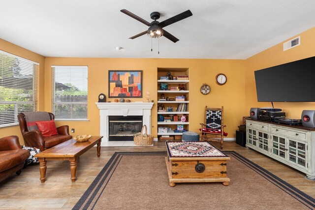 living room featuring a ceiling fan, wood finished floors, and a fireplace with flush hearth