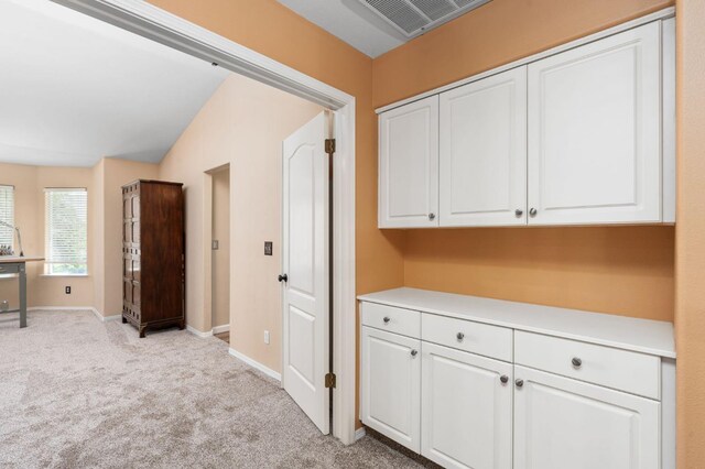 corridor featuring light colored carpet and baseboards