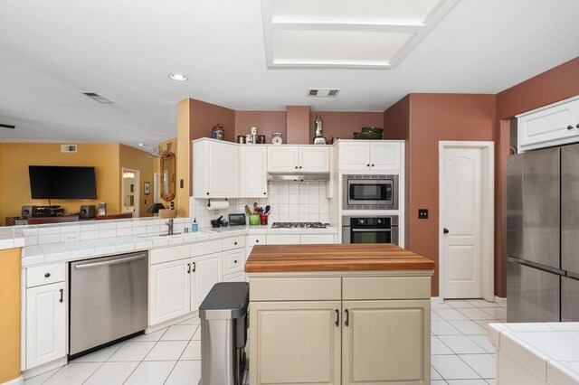 kitchen featuring stainless steel appliances, a sink, open floor plan, light tile patterned floors, and recessed lighting