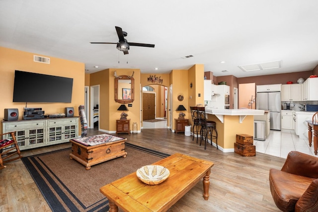 living area featuring a ceiling fan, light wood-type flooring, arched walkways, and baseboards
