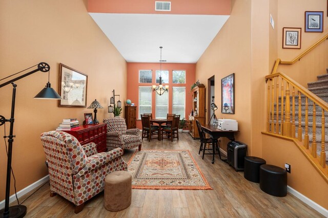 living area featuring stairway, a chandelier, wood finished floors, and baseboards