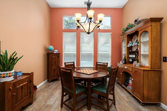 dining space with a chandelier, light wood finished floors, and baseboards