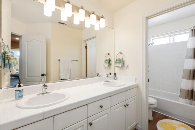 bathroom featuring double vanity, toilet, shower / bath combo, and wood finished floors