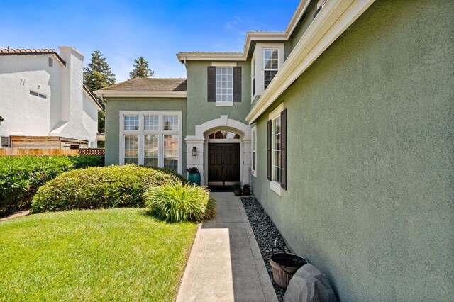 doorway to property with a yard and stucco siding