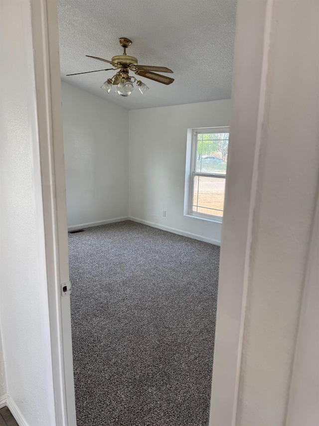 28640 Ward St, Madera, CA 93638 - spare room featuring a textured ceiling, baseboards, a ceiling fan, and dark colored carpet