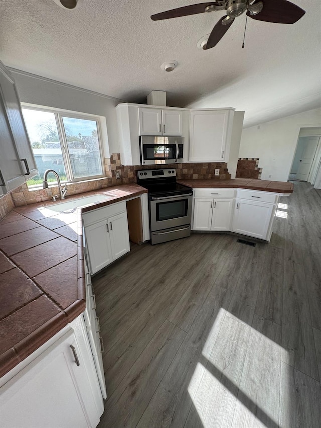 28640 Ward St, Madera, CA 93638 - kitchen with appliances with stainless steel finishes, a sink, dark wood-style floors, white cabinetry, and a textured ceiling