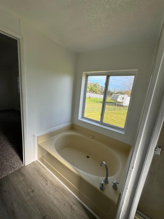 28640 Ward St, Madera, CA 93638 - bathroom featuring a textured ceiling, wood finished floors, and a garden tub