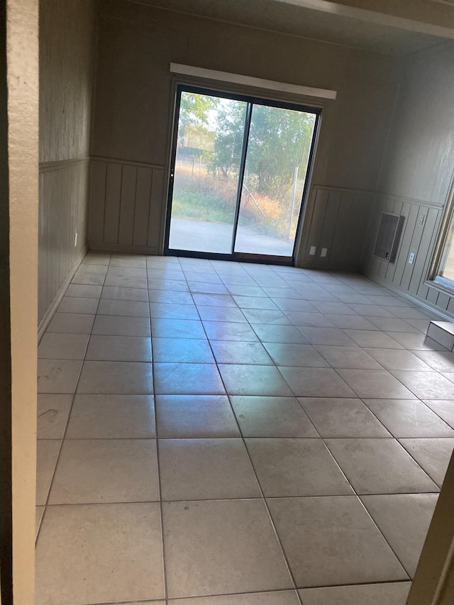 unfurnished room featuring light tile patterned flooring, a decorative wall, and a wainscoted wall