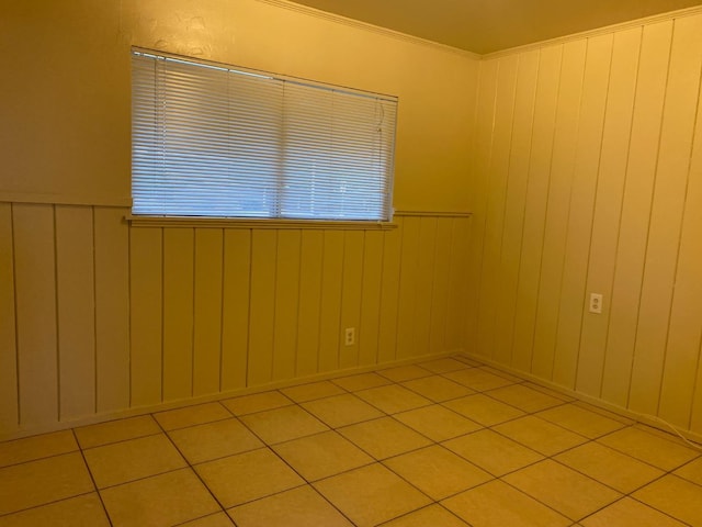 spare room featuring wainscoting, tile patterned floors, and crown molding