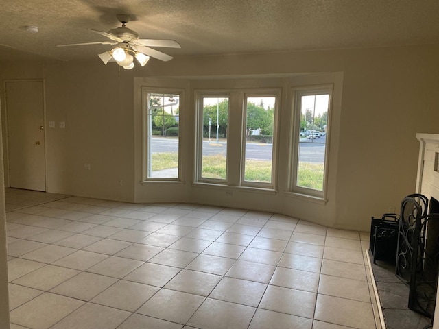 empty room with a textured ceiling, light tile patterned floors, a ceiling fan, and a smoke detector