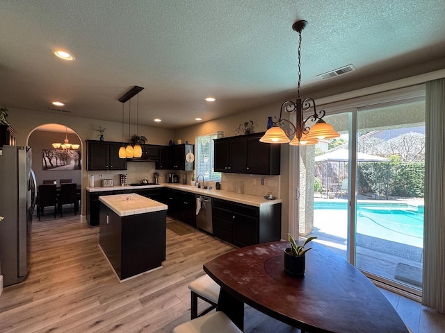 1822 N Magnolia, Clovis, CA 93619 - kitchen with a chandelier, stainless steel appliances, a kitchen island, light countertops, and tasteful backsplash