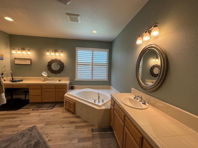 1822 N Magnolia, Clovis, CA 93619 - bathroom with wood finished floors, a textured ceiling, a garden tub, two vanities, and recessed lighting