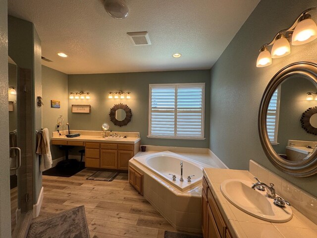 1822 N Magnolia, Clovis, CA 93619 - full bathroom featuring wood finished floors, a garden tub, a textured ceiling, two vanities, and recessed lighting