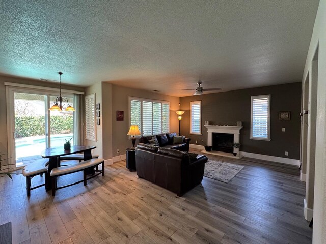 1822 N Magnolia, Clovis, CA 93619 - living area with a textured ceiling, a ceiling fan, a fireplace with raised hearth, light wood-style flooring, and baseboards