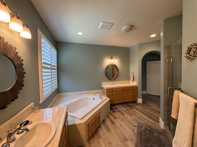 1822 N Magnolia, Clovis, CA 93619 - bathroom with two vanities, a shower stall, a bath, wood finished floors, and recessed lighting