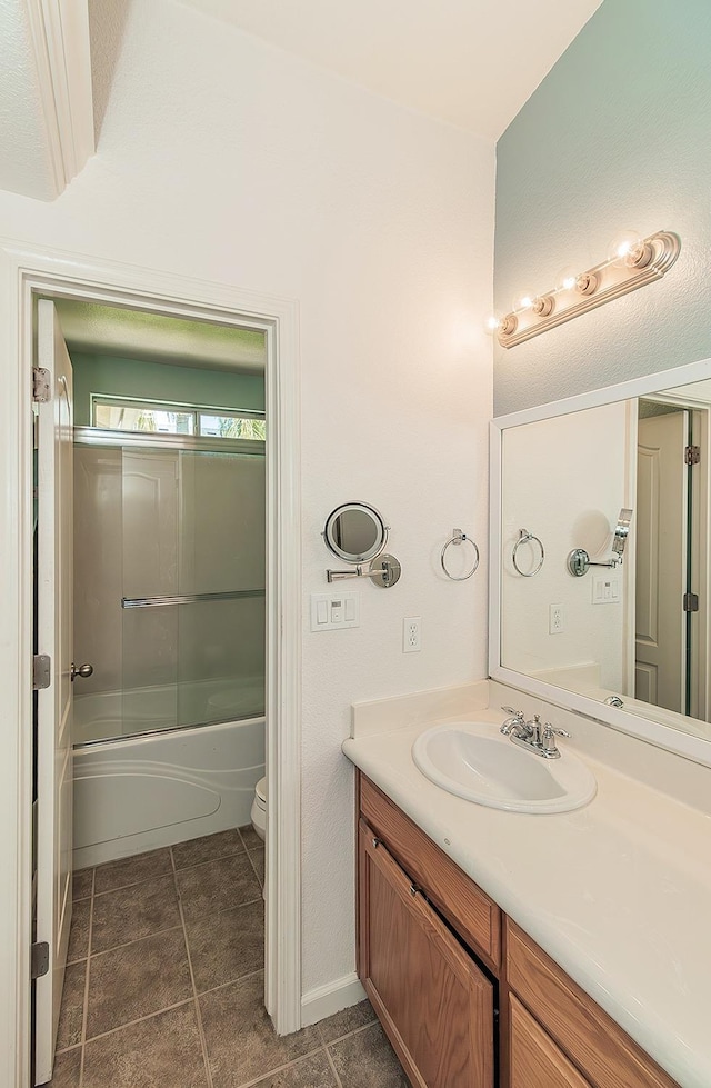 6588 E Lowe Ave, Fresno, CA 93727 - full bathroom featuring vanity, toilet, tile patterned floors, and bath / shower combo with glass door