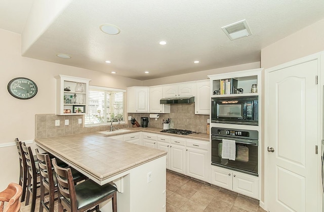 6588 E Lowe Ave, Fresno, CA 93727 - kitchen with open shelves, black appliances, a breakfast bar, a peninsula, and recessed lighting