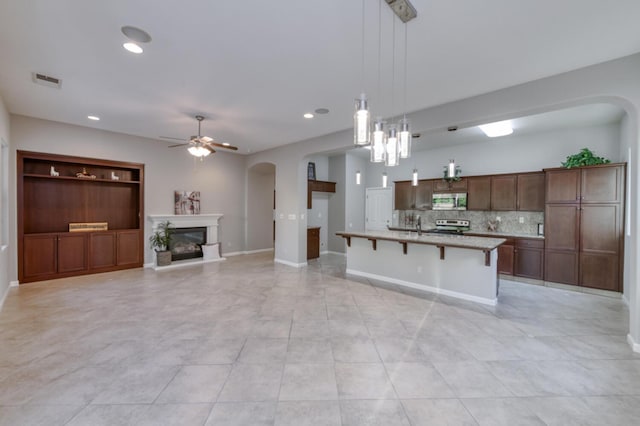 kitchen featuring appliances with stainless steel finishes, arched walkways, a ceiling fan, decorative backsplash, and hanging light fixtures