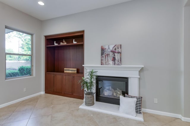 living room featuring light tile patterned floors, baseboards, recessed lighting, and a glass covered fireplace
