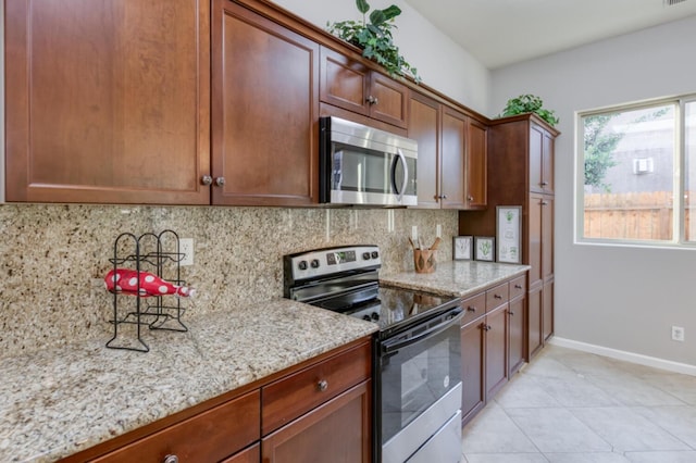 kitchen featuring appliances with stainless steel finishes, backsplash, baseboards, and light stone counters