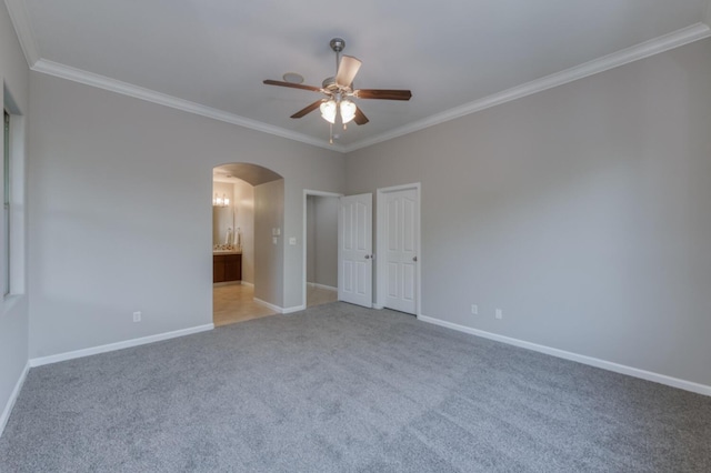 unfurnished bedroom with arched walkways, baseboards, ornamental molding, carpet, and ensuite bath