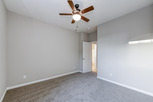 carpeted spare room featuring ceiling fan and baseboards