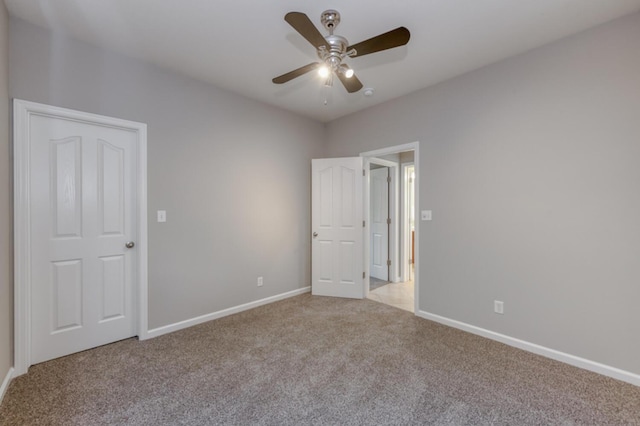 unfurnished bedroom with light colored carpet, baseboards, and a ceiling fan
