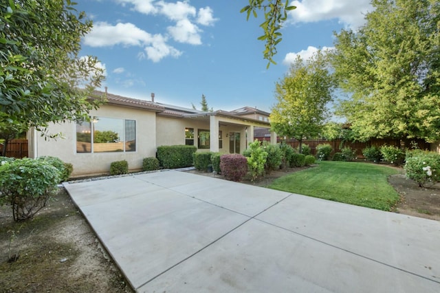 rear view of property with solar panels, a patio area, and stucco siding
