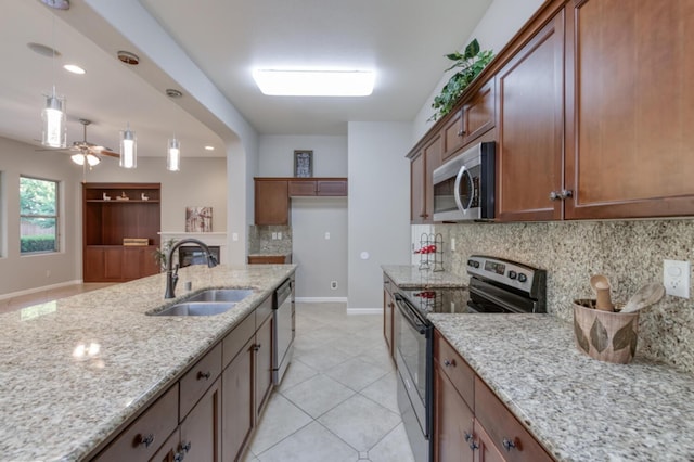 kitchen with appliances with stainless steel finishes, a sink, backsplash, baseboards, and light stone countertops