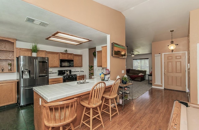 3042 Love St, Selma, CA 93662 - kitchen with black appliances, a sink, brown cabinets, a peninsula, and a breakfast bar area