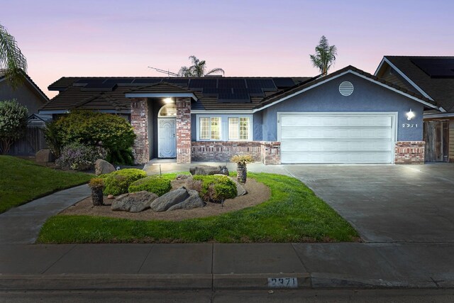 2371 Sophia Ln, Kingsburg, CA 93631 - ranch-style house featuring a garage, concrete driveway, solar panels, brick siding, and stucco siding