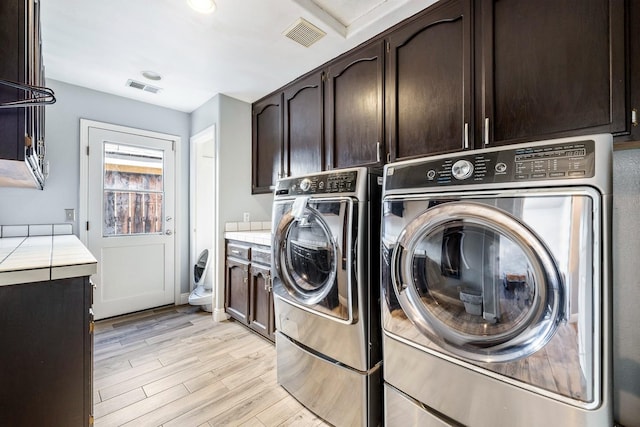 2371 Sophia Ln, Kingsburg, CA 93631 - laundry room featuring cabinet space, washing machine and clothes dryer, and light wood-style floors