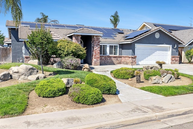 2371 Sophia Ln, Kingsburg, CA 93631 - ranch-style home with brick siding, stucco siding, roof mounted solar panels, an attached garage, and driveway