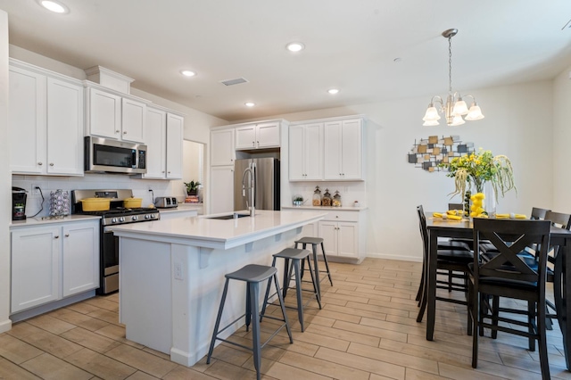 6458 E Riesling Dr, Fresno, CA 93727 - kitchen featuring stainless steel appliances, wood tiled floors, backsplash, white cabinetry, and recessed lighting