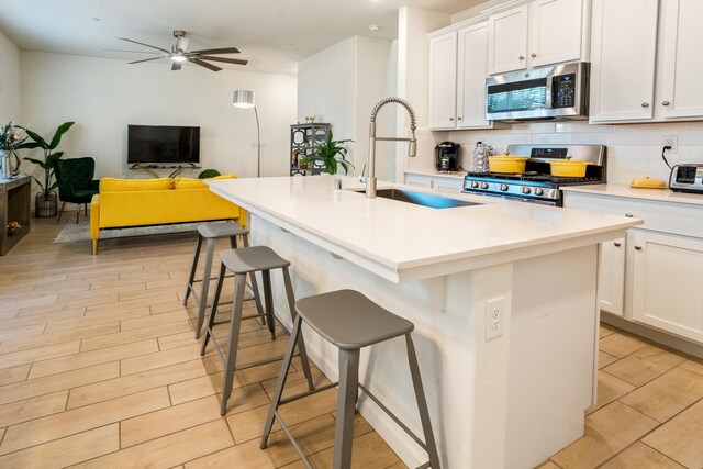 6458 E Riesling Dr, Fresno, CA 93727 - kitchen featuring stainless steel appliances, a sink, a breakfast bar, tasteful backsplash, and an island with sink