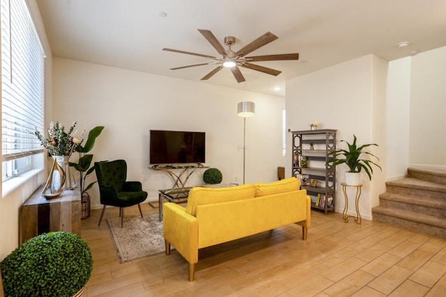 6458 E Riesling Dr, Fresno, CA 93727 - living room featuring light wood-style flooring, a ceiling fan, healthy amount of natural light, and stairs