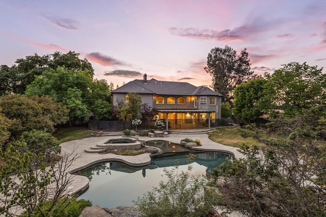 2758 N Highland Ave, Fresno, CA 93737 - back of property at dusk featuring an in-ground hot tub, a fenced backyard, a patio area, an outdoor pool, and stucco siding